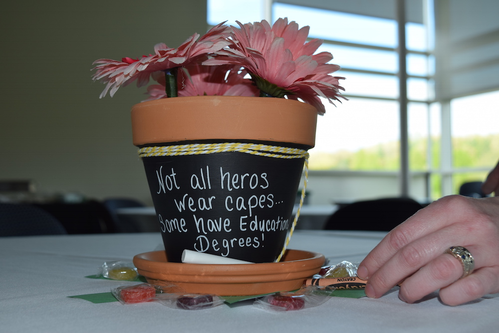 A plant pot that reads "Not all heros wear capes. Some have education degrees."